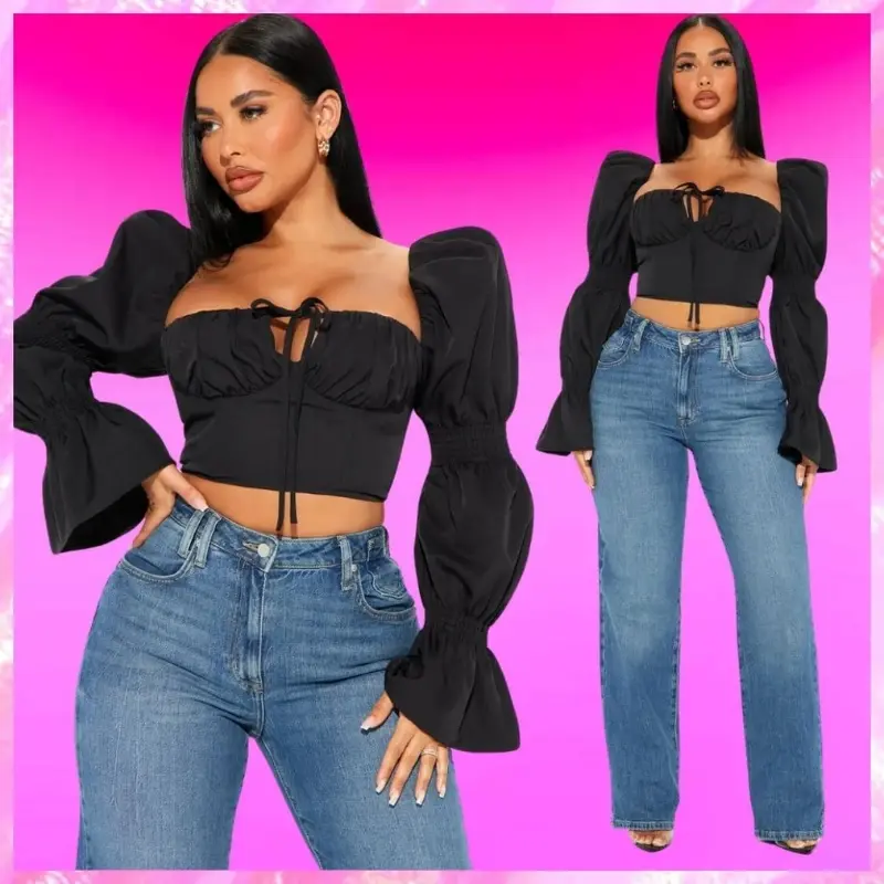 Model wearing a black puff sleeve crop top and blue wide-leg jeans against a plain background.